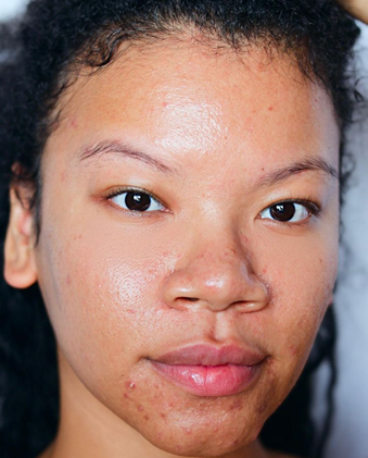 Florence has light brown skin, and full pinkish lips. She has brown eyes, and she has a pleasant look on her face. She is wearing no makeup, and she has thick, curly hair.