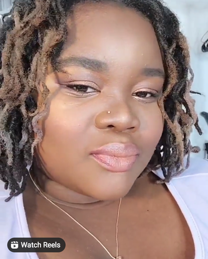 Karessa has wavey locs. Her skin is chocolate brown. She takes a selfie and looks at peace.